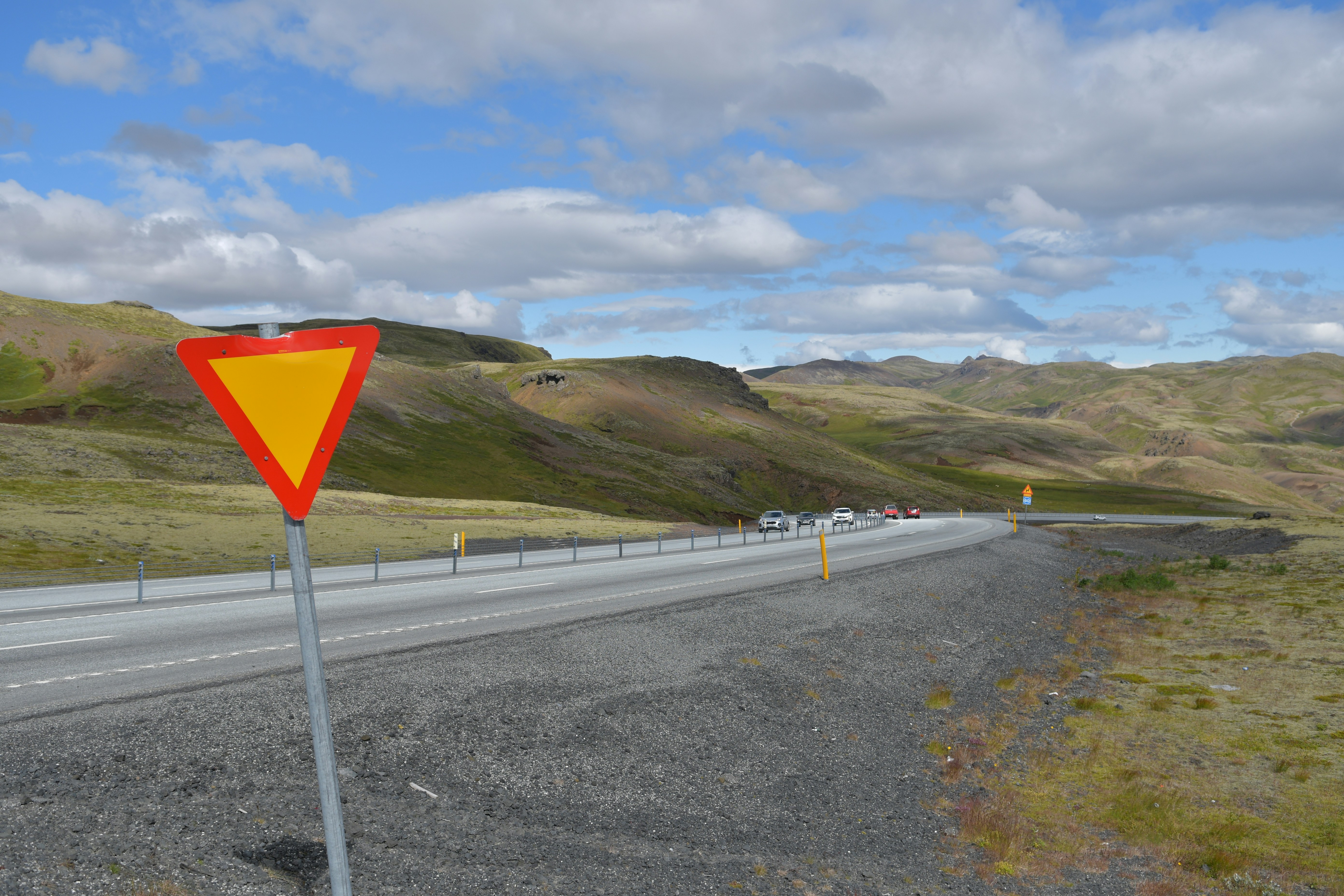 Segnale di precedenza su una strada tortuosa attraverso le colline.