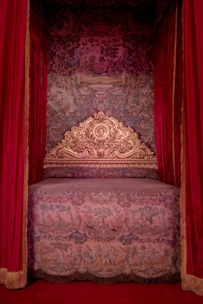 A regal bed with ornate gold headboard.