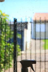 Raindrops streak down a window with spray bottle.