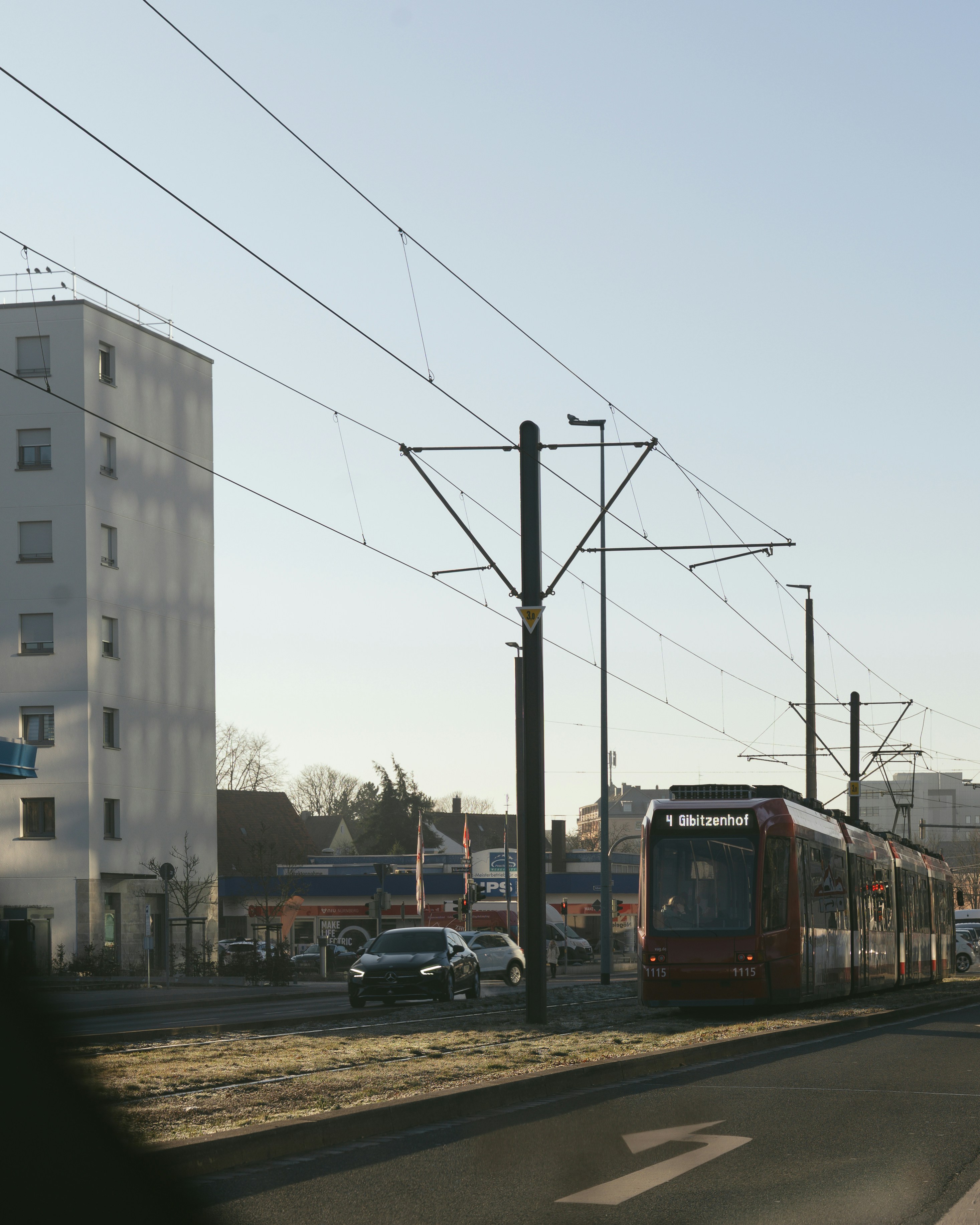 A red train is passing by the city street.
