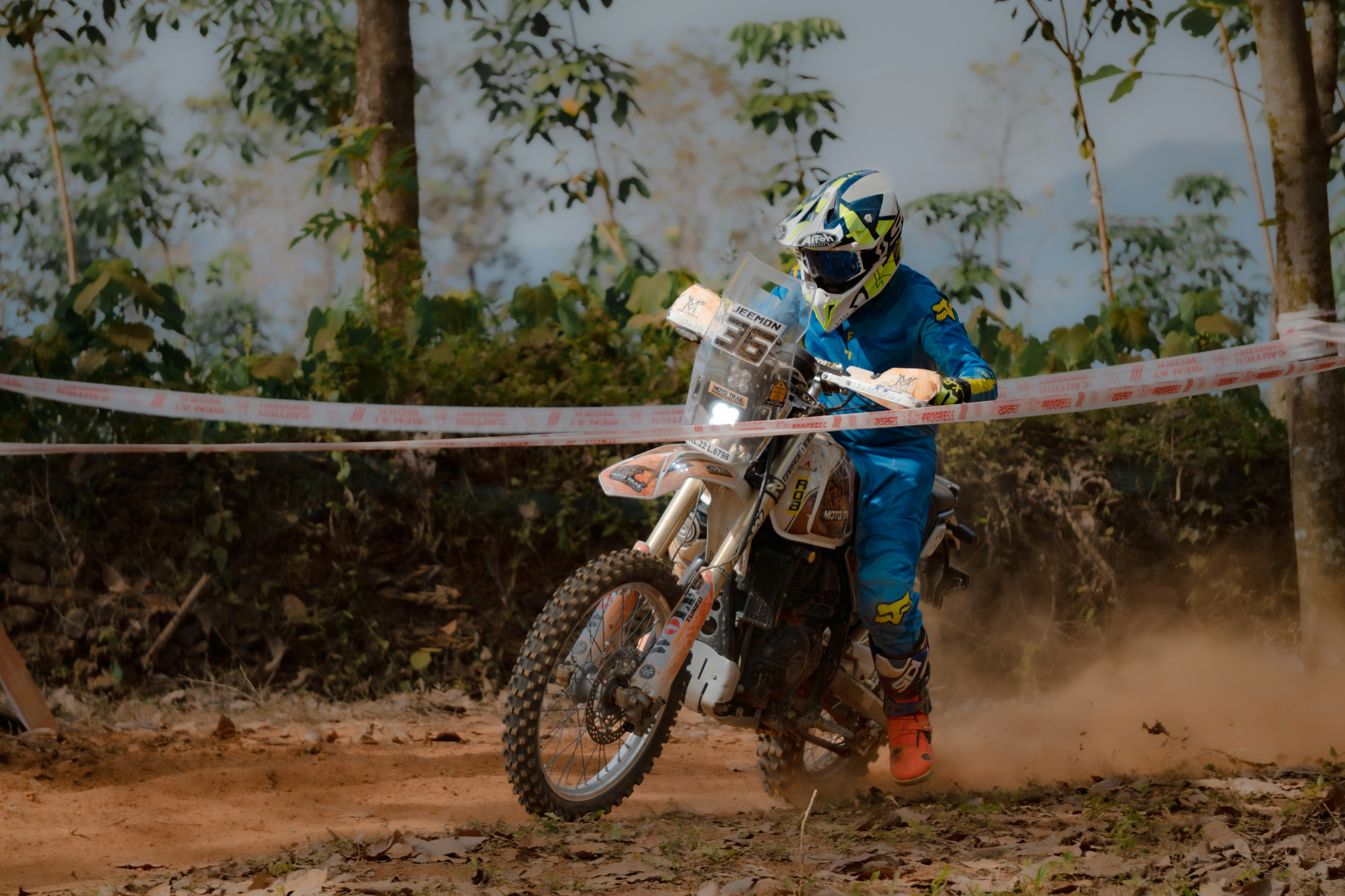 A motorcyclist races through a dusty forest trail