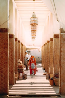 People walk through a market corridor lined with pillars.