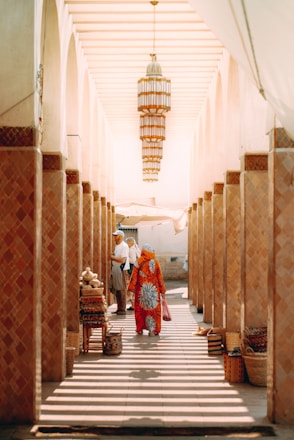 People walk through a market corridor lined with pillars.
