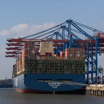 A cargo ship is being unloaded at the harbor.