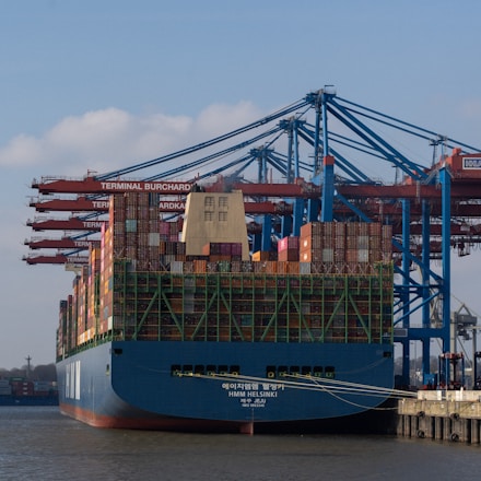 A cargo ship is being unloaded at the harbor.