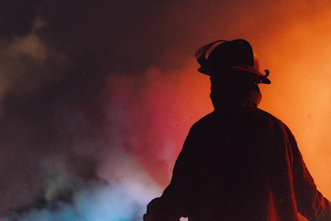 A firefighter silhouetted against smoke