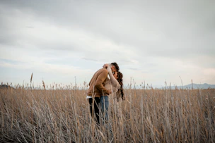 Couple shares a kiss in a field.