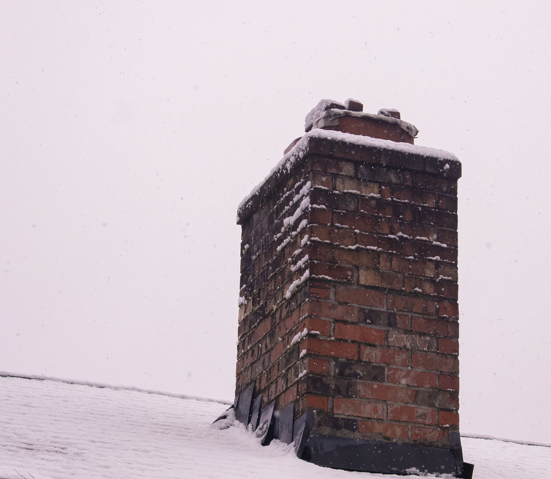 A brick chimney covered in fresh snow.