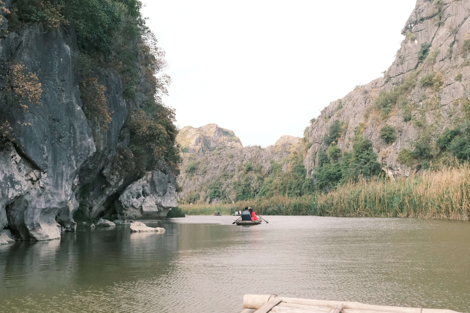 Boat travelling through a limestone mountain river landscape in Ninh Binh, Vietnam