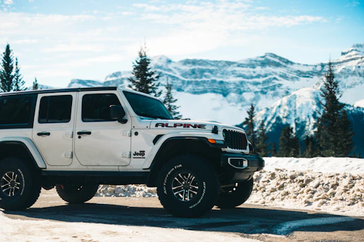 A white jeep is parked in a mountainous landscape.