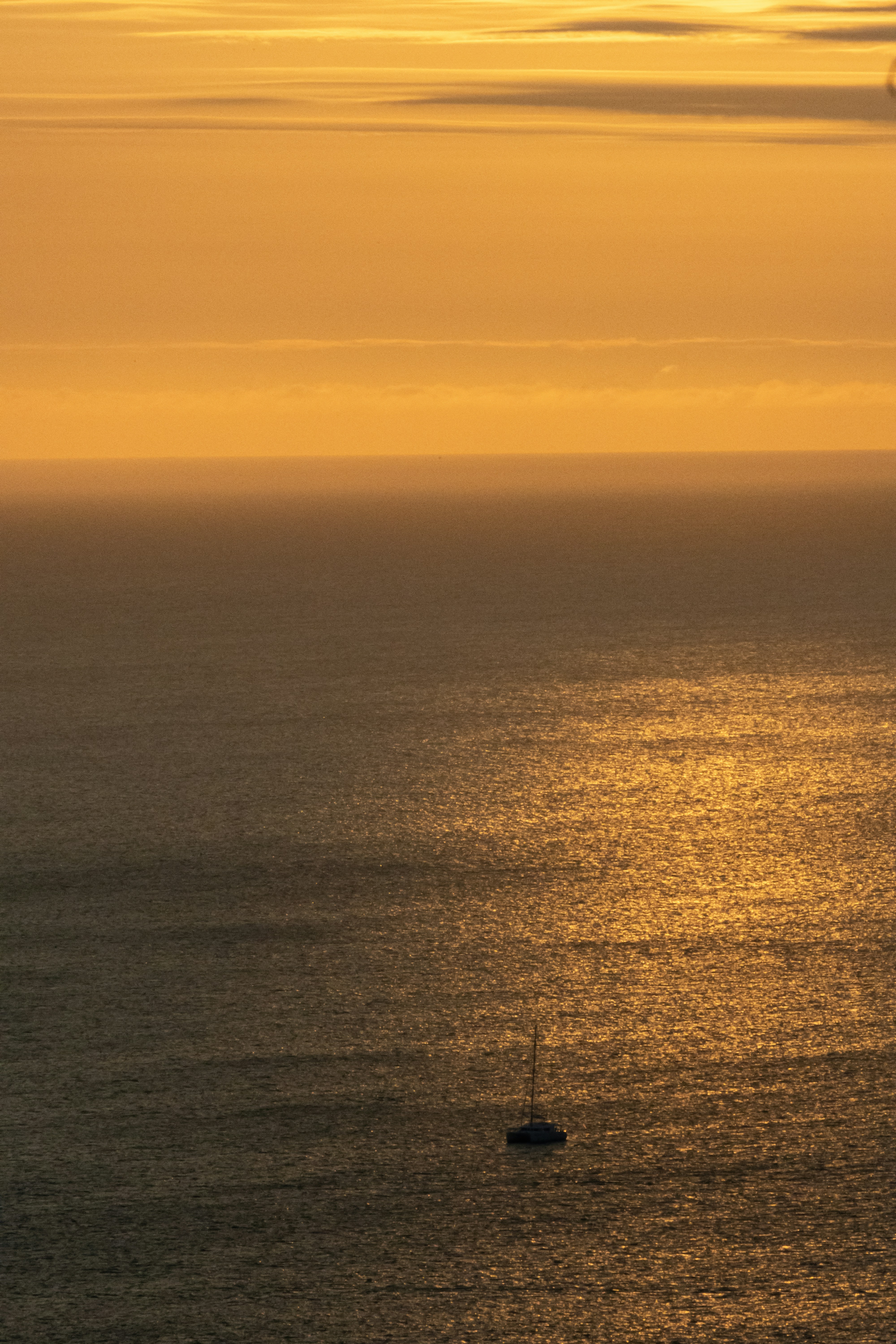 Golden sunset over the ocean with a sailboat.