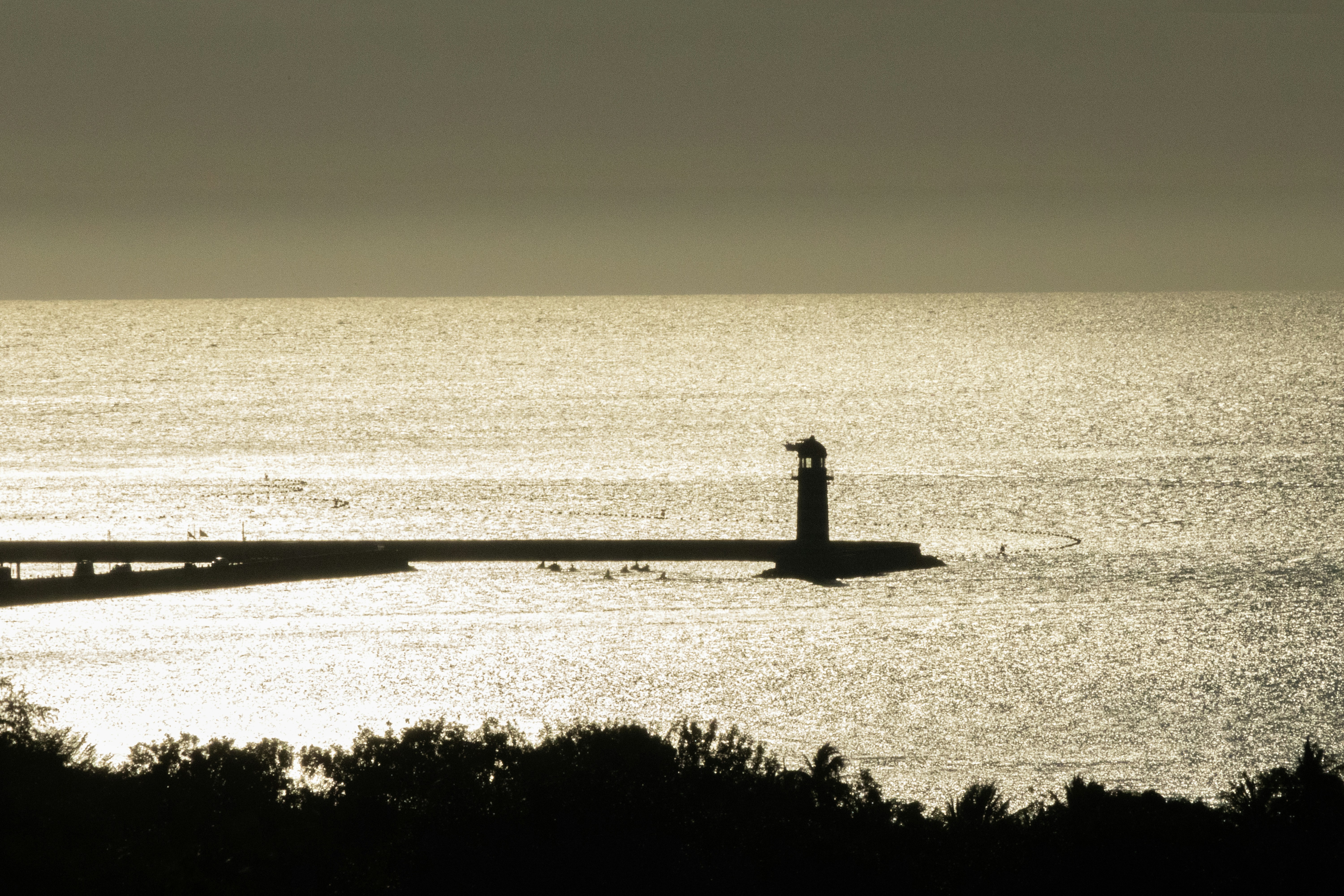 A lighthouse stands on a pier at sunset.