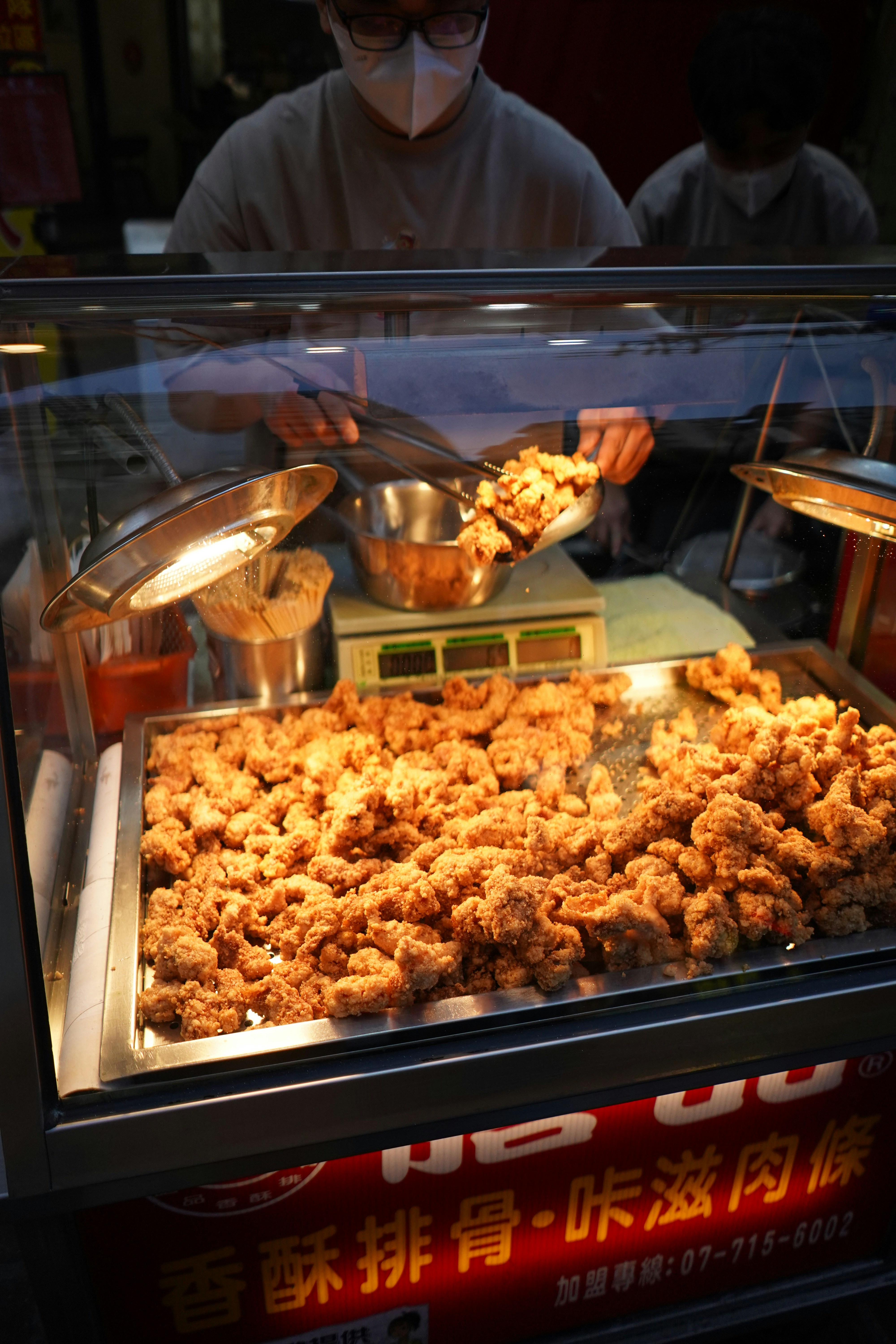 Freshly fried chicken is being served at a food stall.