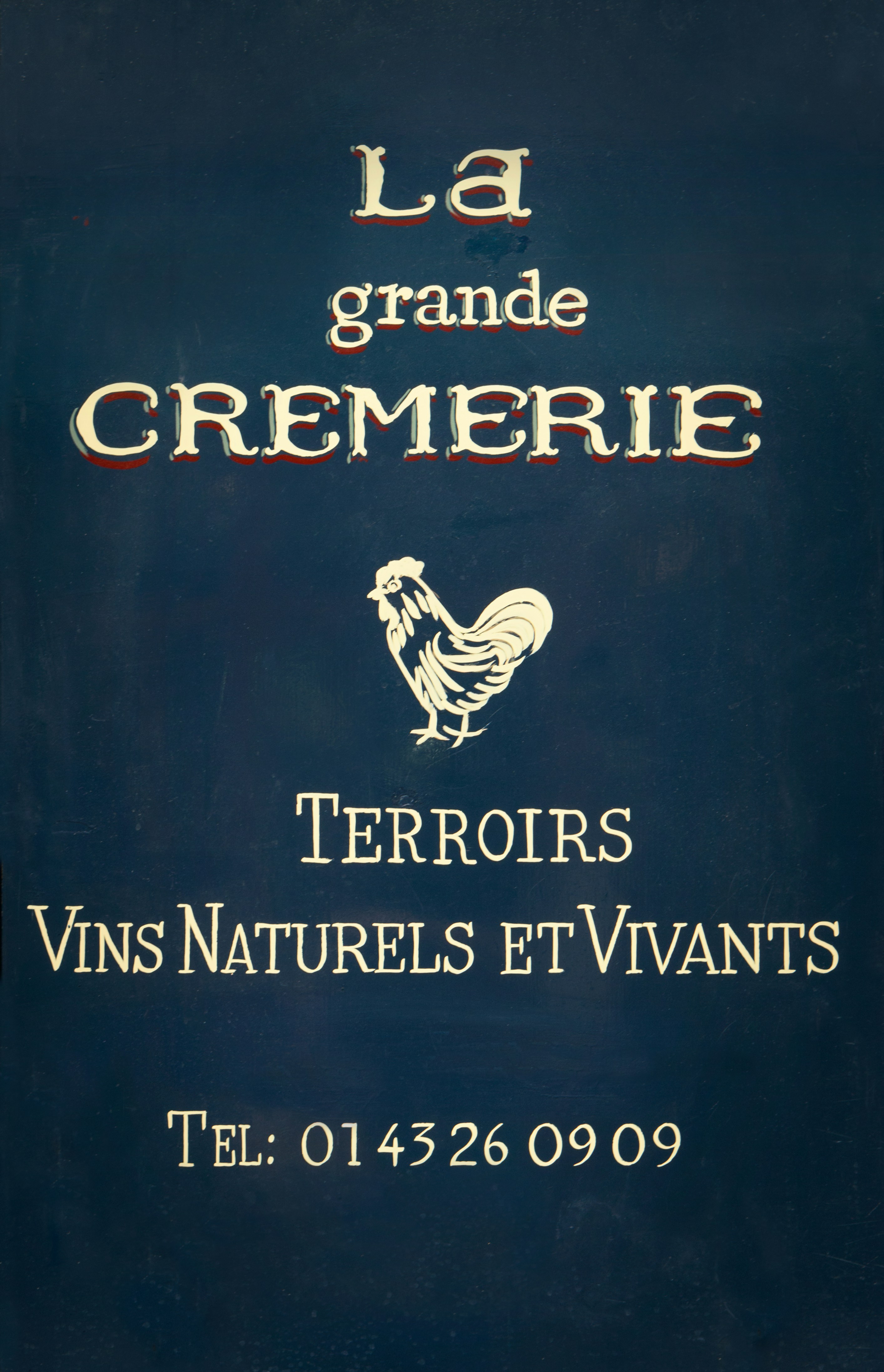 Enseigne de boutique française bleu foncé avec un coq blanc.