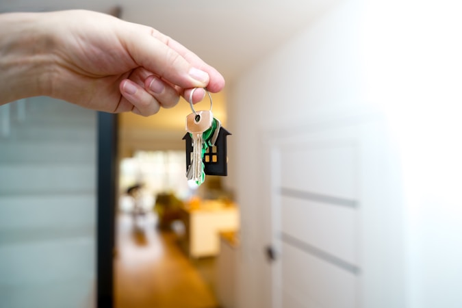 A hand holding house keys in front of a front door after closing on a home