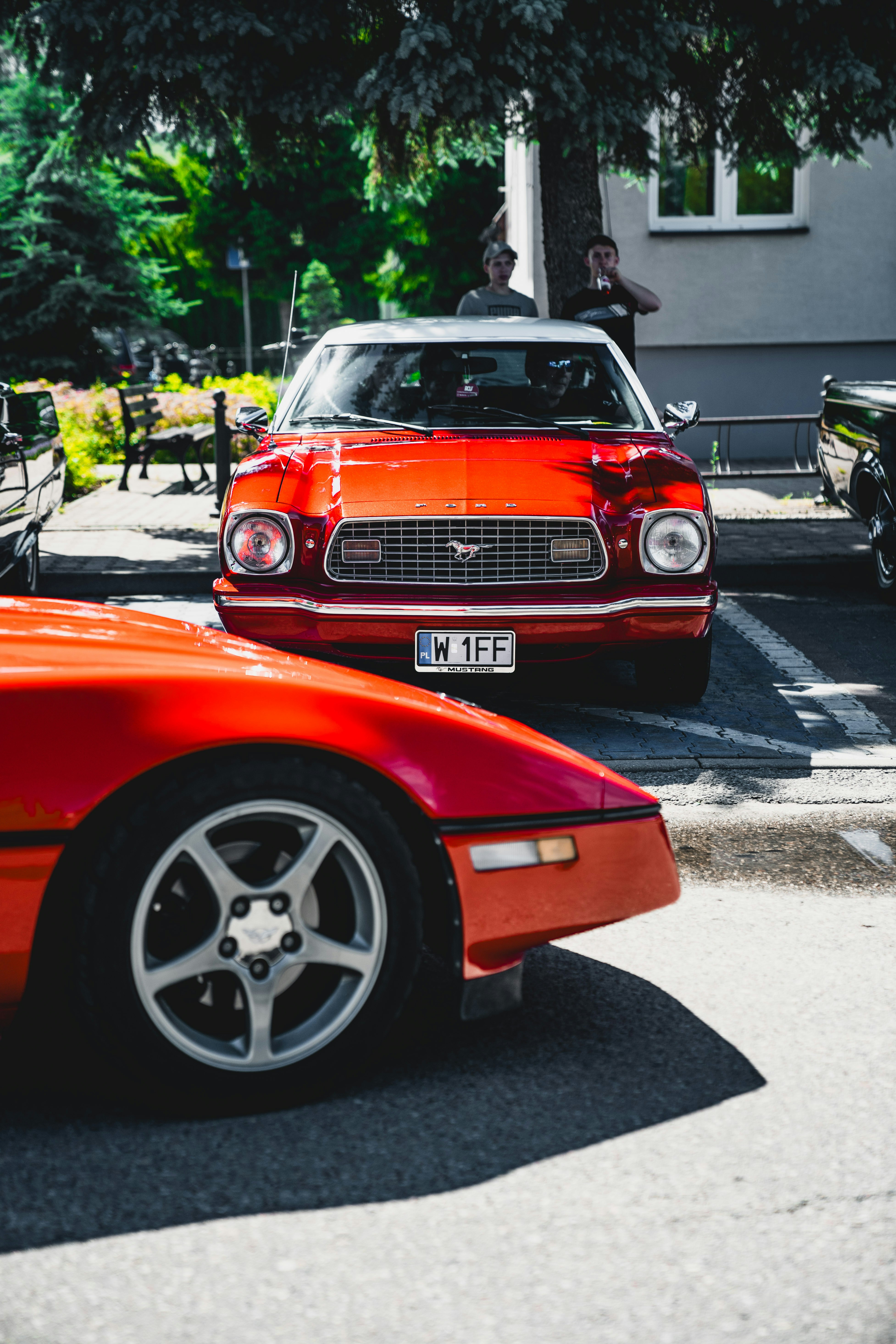 Classic red cars parked outdoors in the daytime.