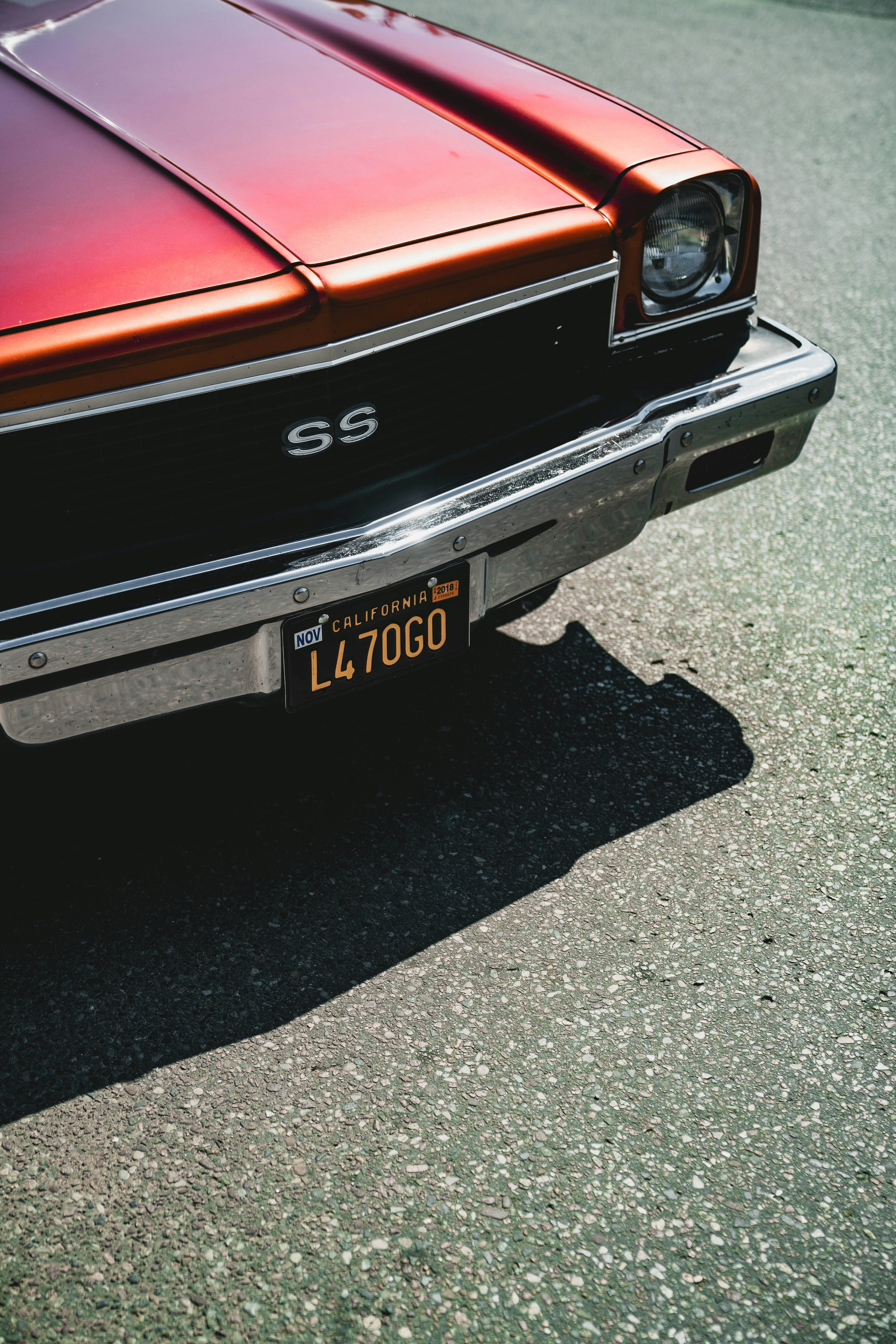 A classic red ss car sits in the sun.
