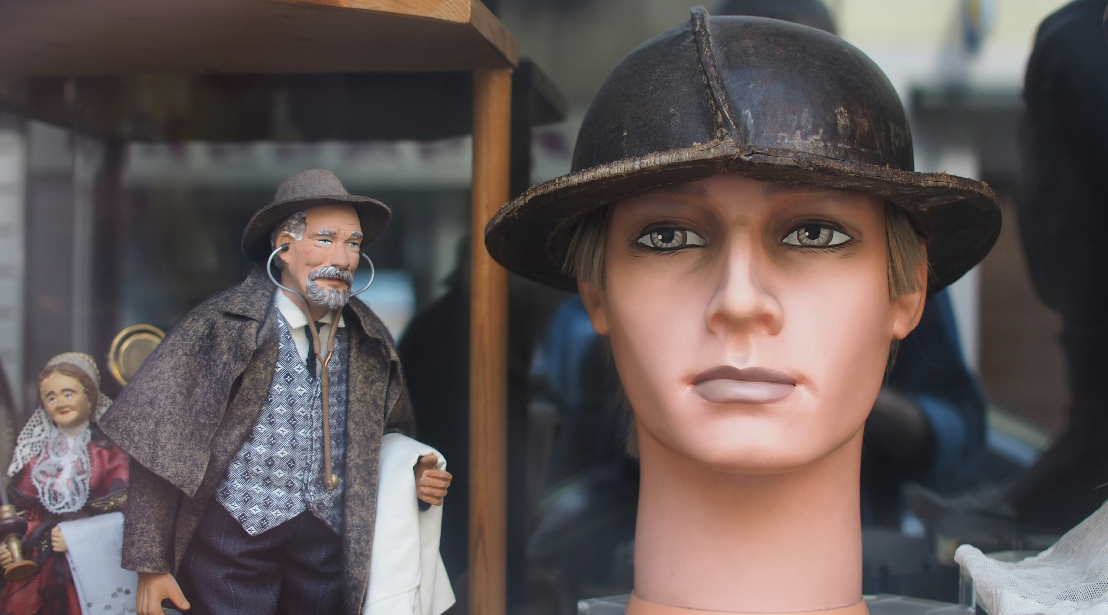A mannequin wears a hat with figurines in the background.
