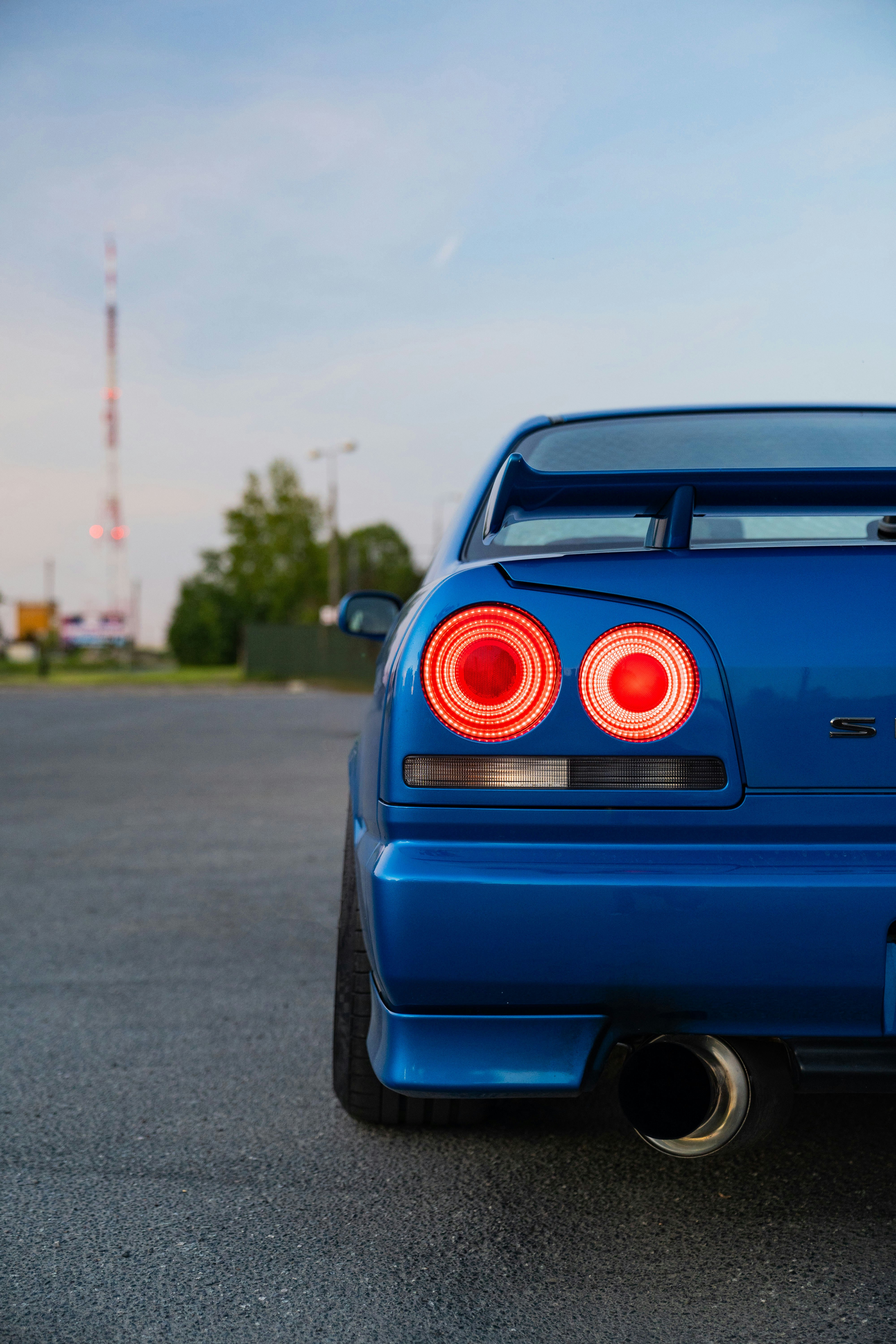 Blue nissan skyline r34 parked with lights on.