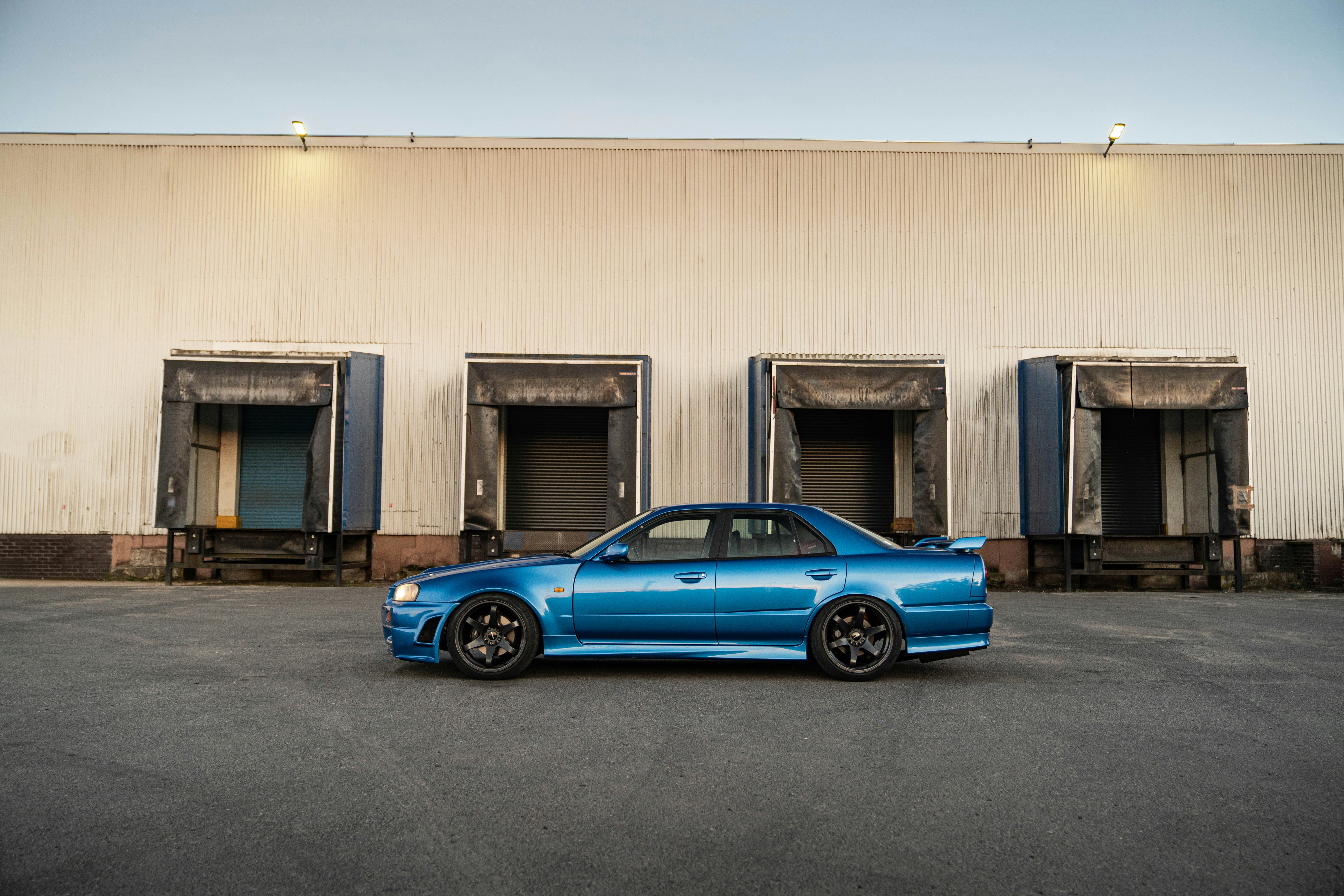 A blue sports car parked in front of warehouse.
