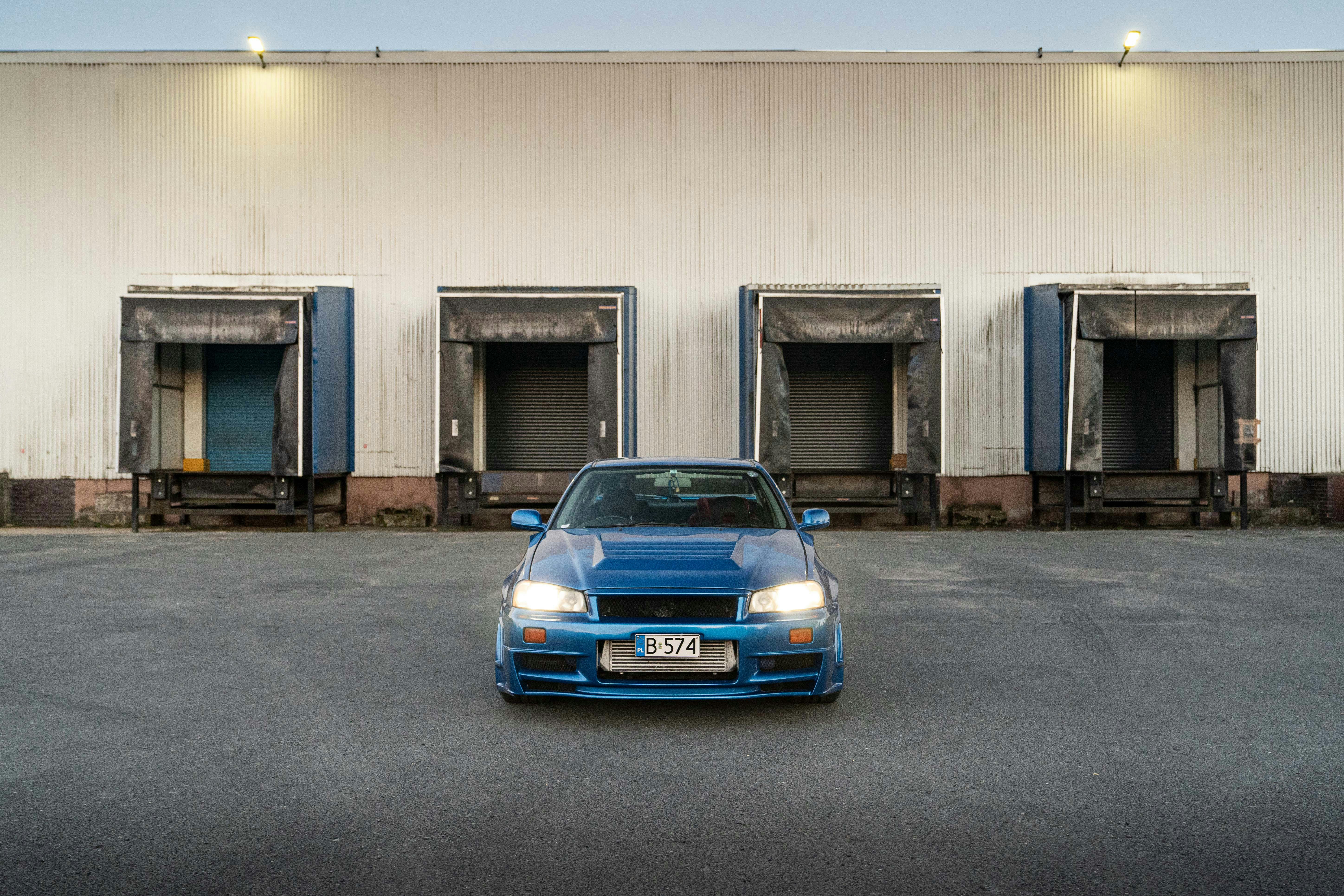 A blue sports car parks in front of loading docks.