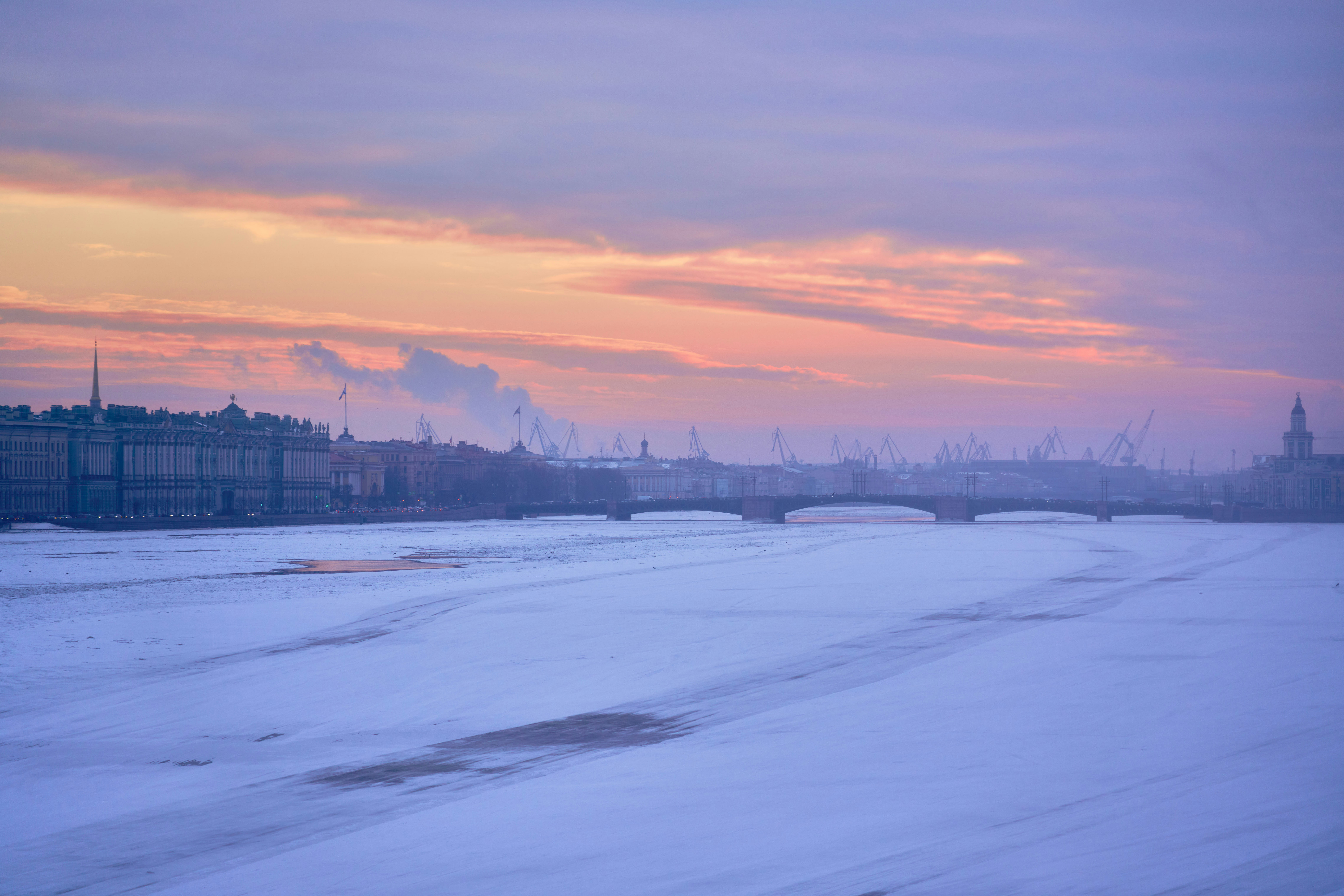 Frozen river and city buildings at dawn.