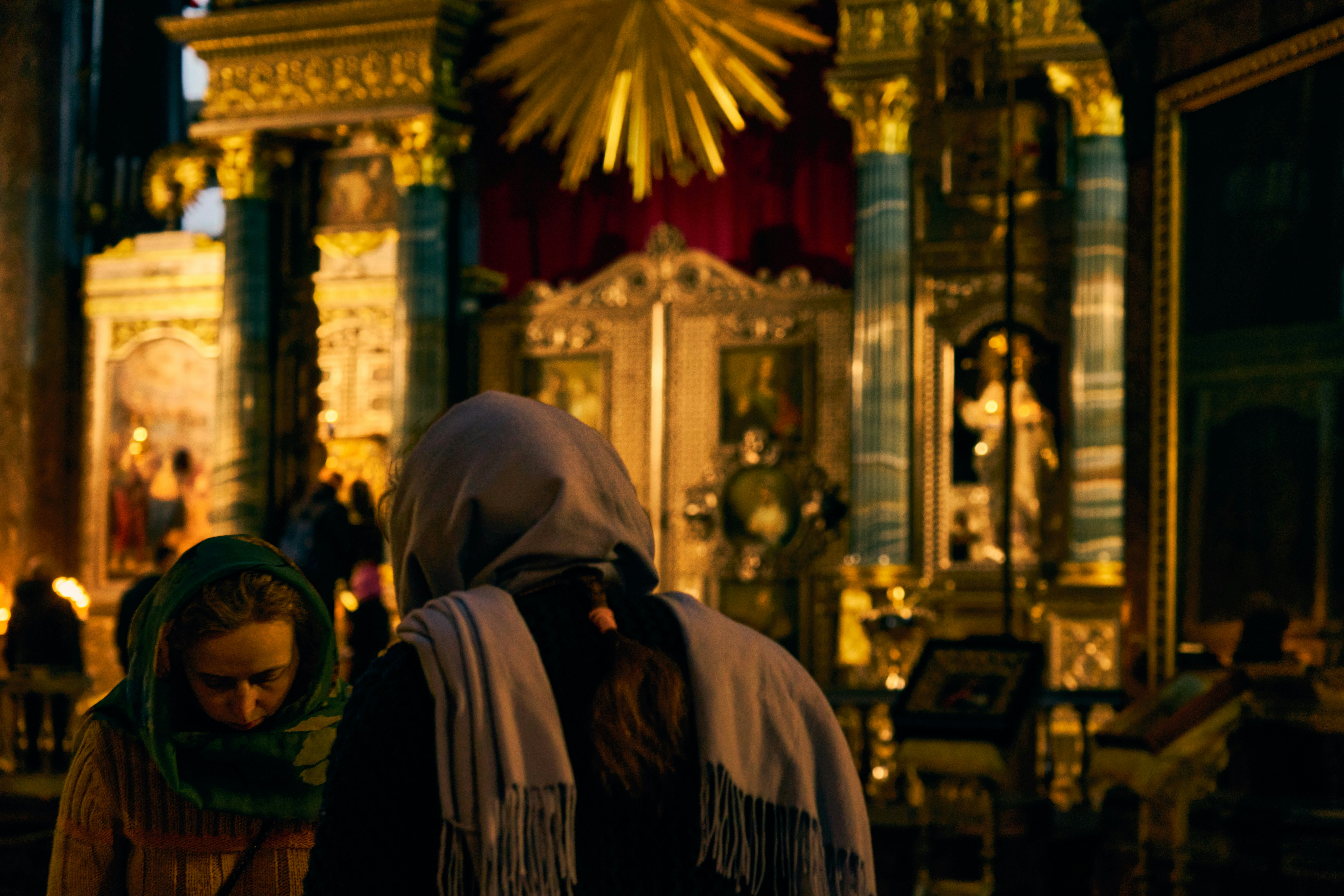 People are praying in a dimly lit church.