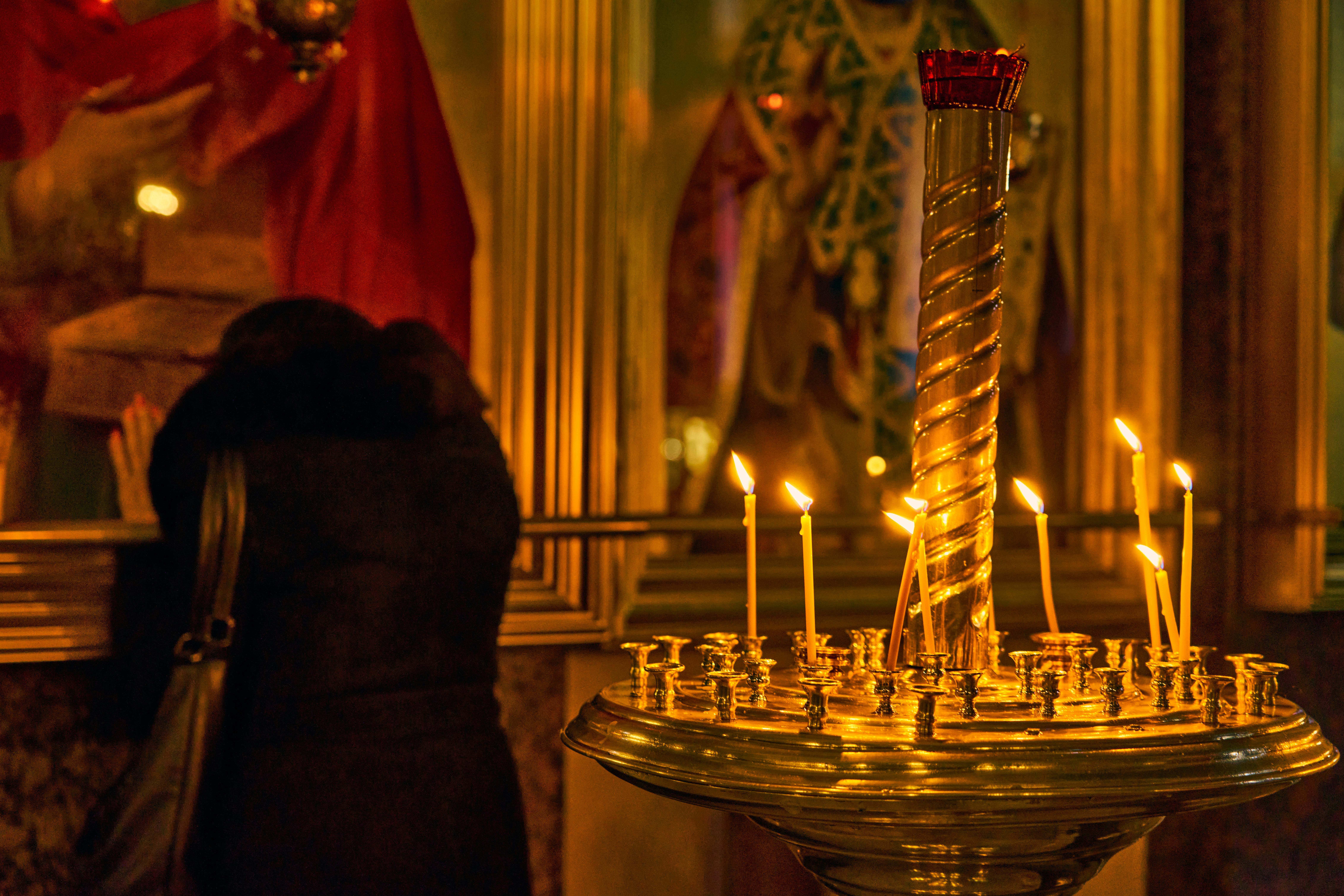 Woman prays near candles in a church.