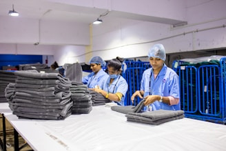 Workers fold and stack clean towels in a laundry.