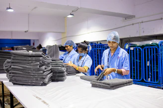 Workers fold and stack clean towels in a laundry.