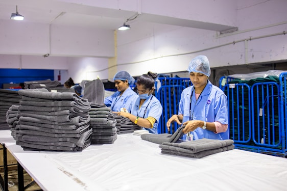 Workers fold and stack clean towels in a laundry.