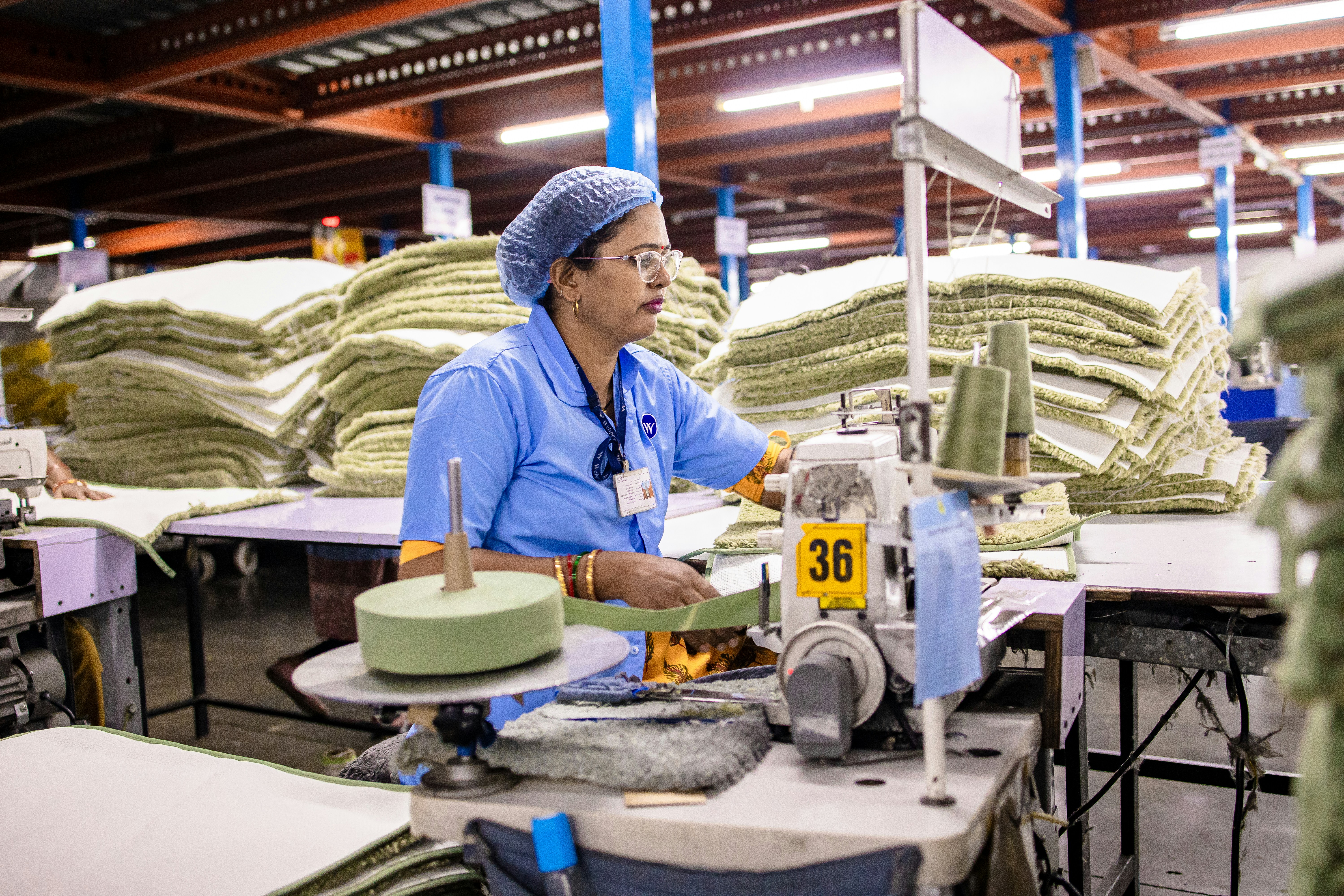 A woman sews fabric in a factory.