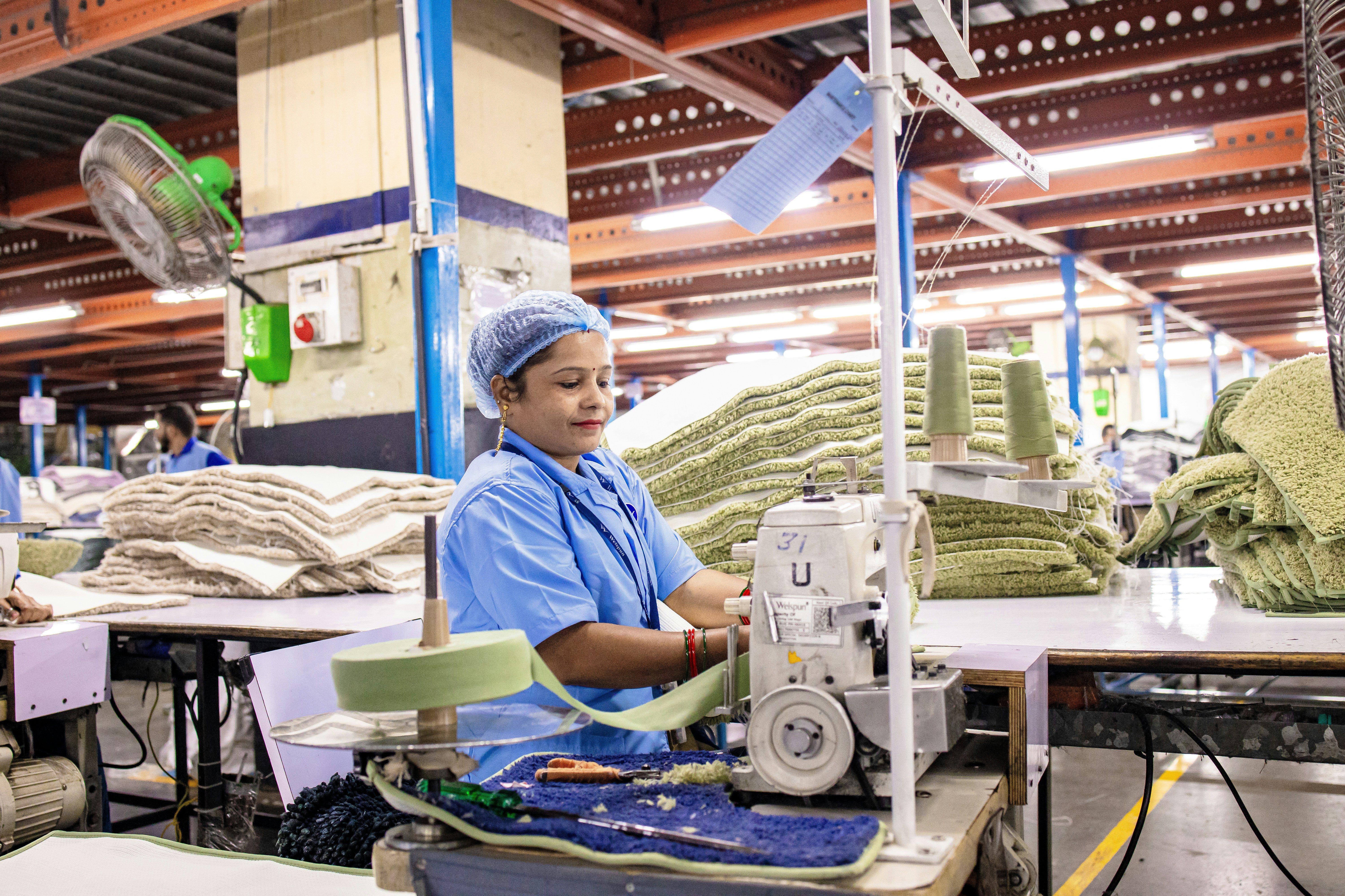 Une femme coud du tissu à l’aide d’une machine à coudre dans une usine.