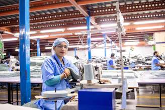 A woman works at a sewing machine in a factory.