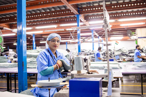 A woman works at a sewing machine in a factory.