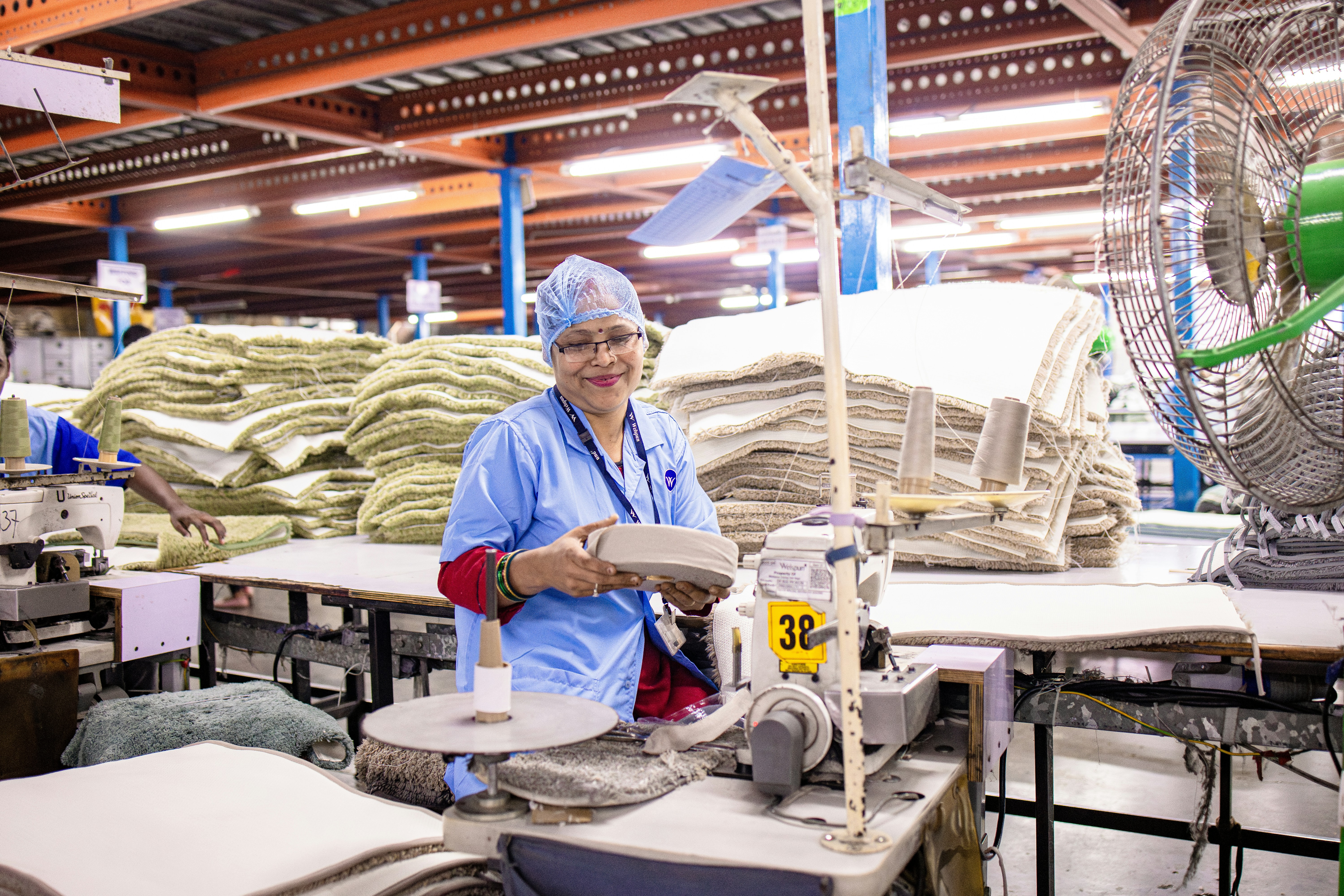 Femme travaillant dans une usine textile avec des matériaux.