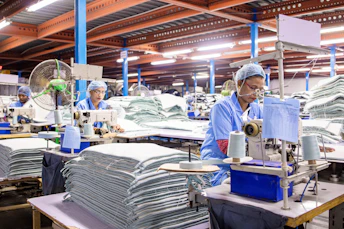 Workers operate sewing machines in a factory.