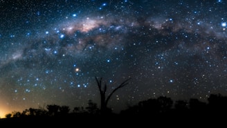 The milky way shines above a dark landscape.