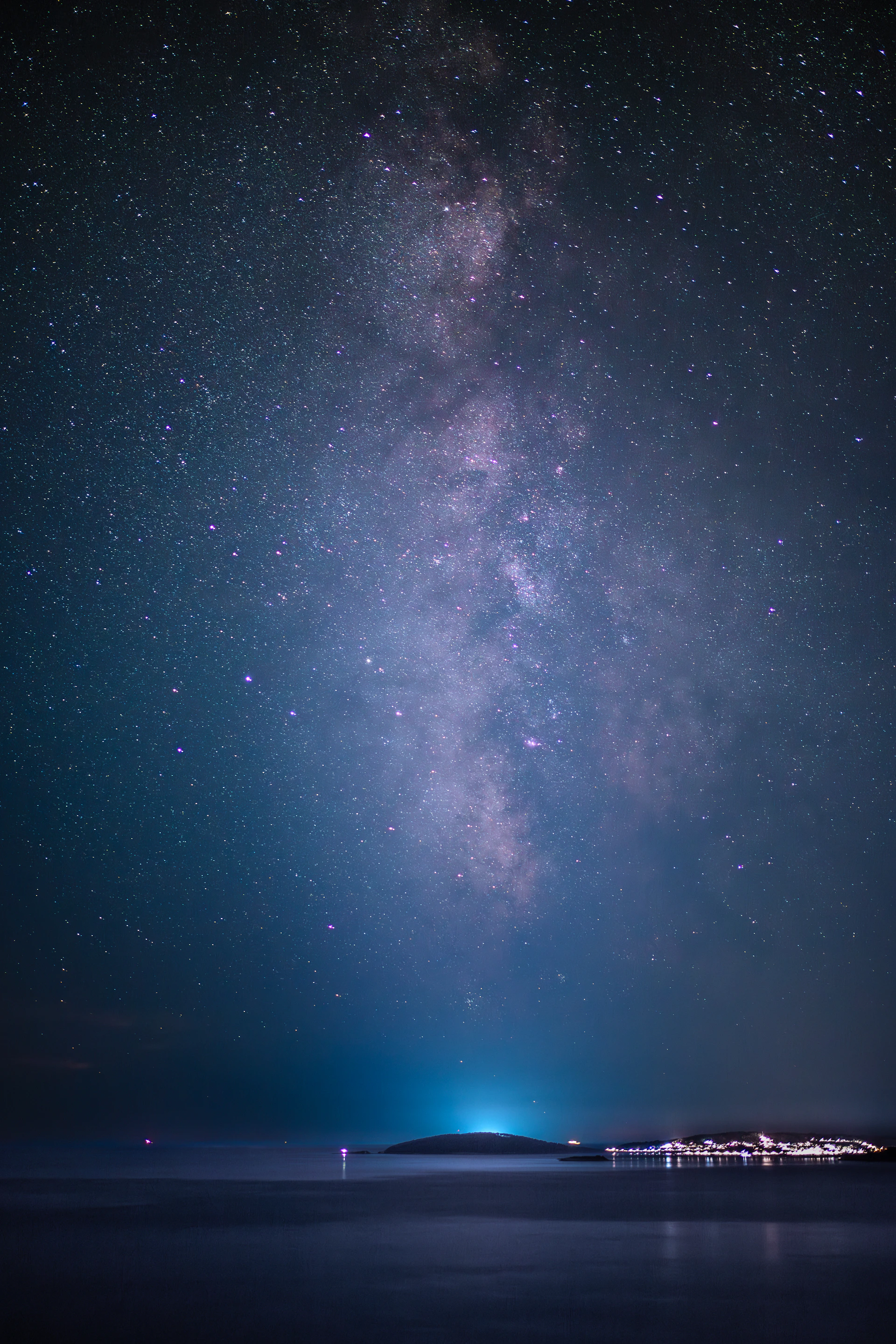 The milky way shines brightly above the ocean.