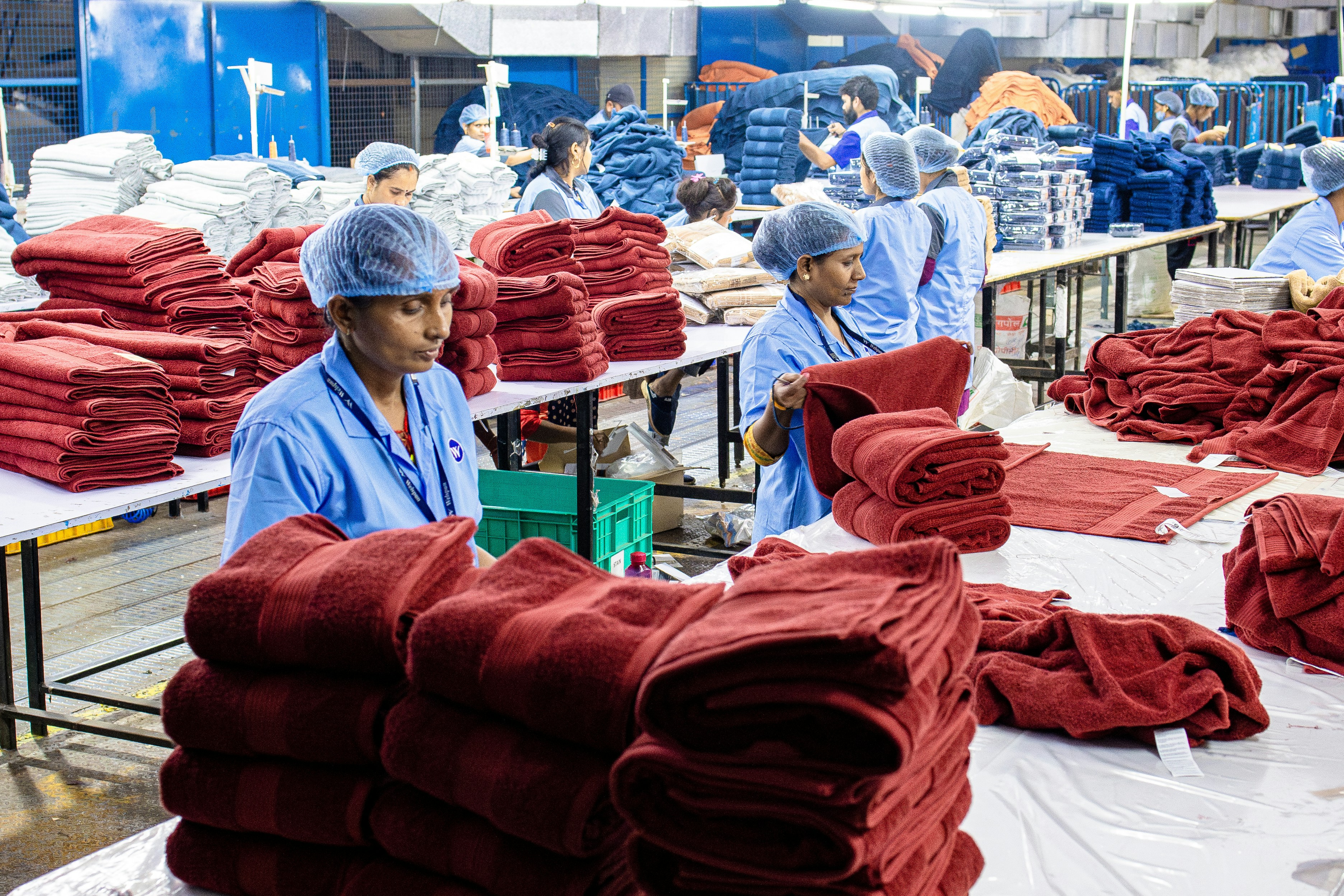 Workers fold and stack textiles in a factory.