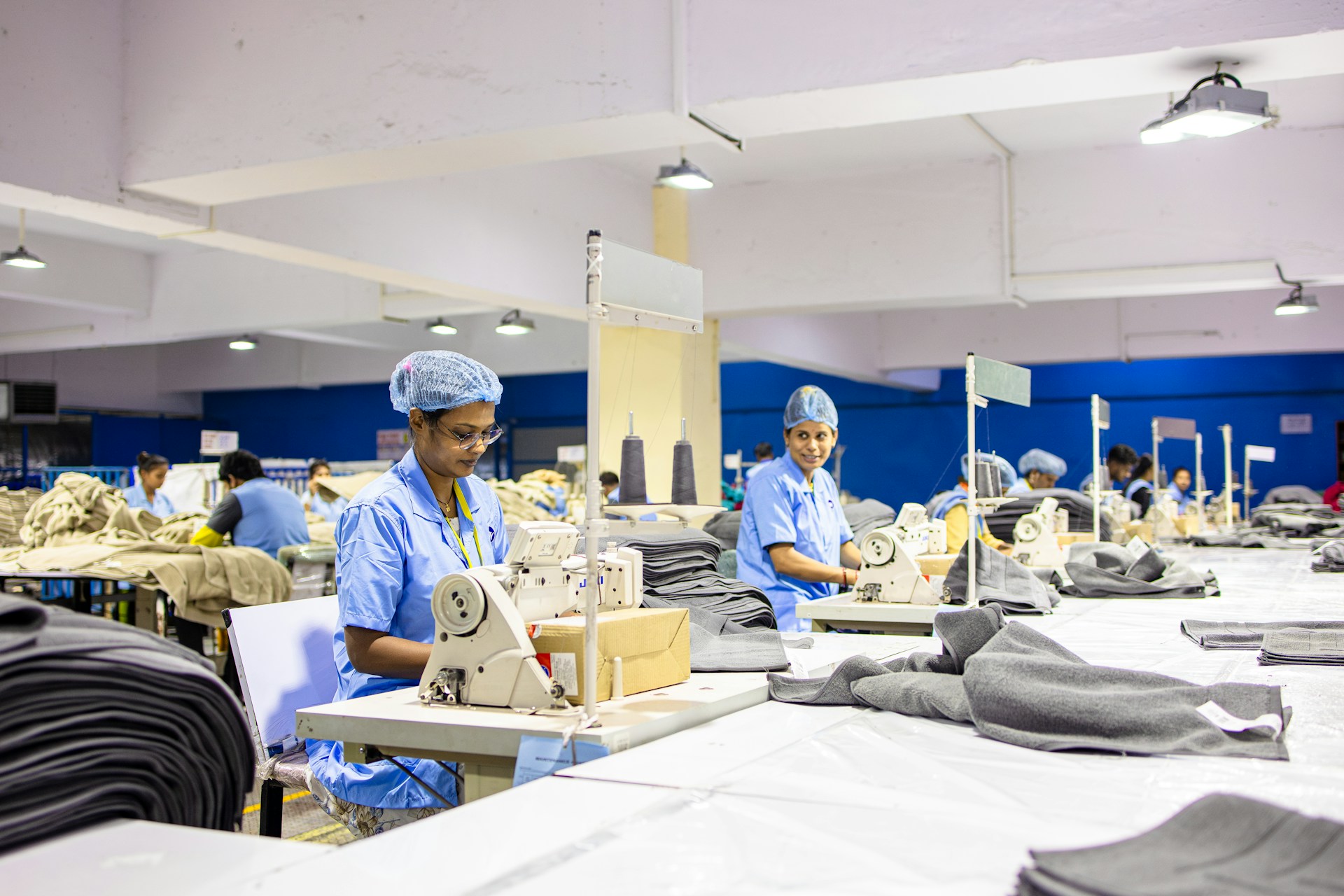 Workers are sewing clothes in a factory setting.