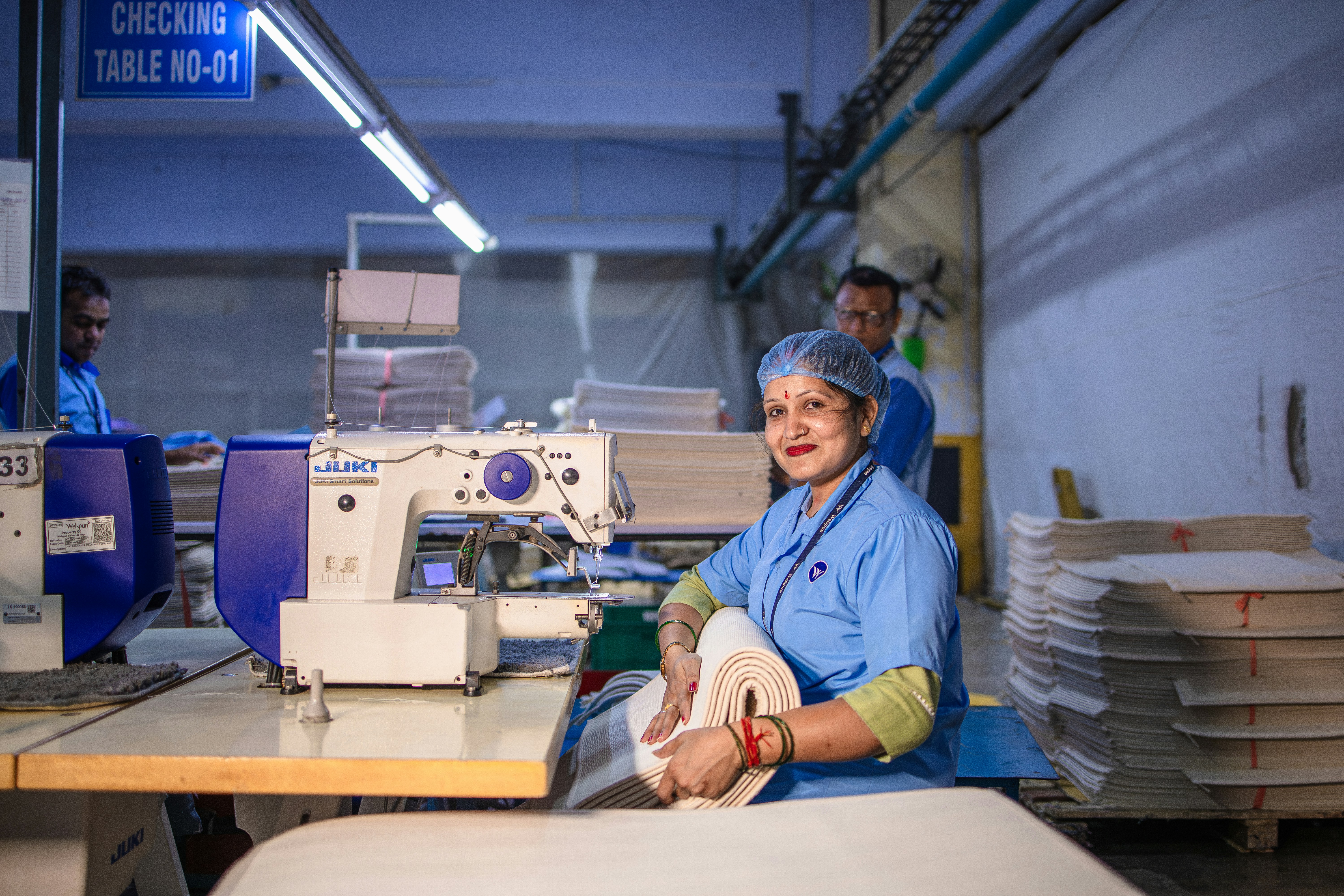 Femme cousant du tissu dans une usine.