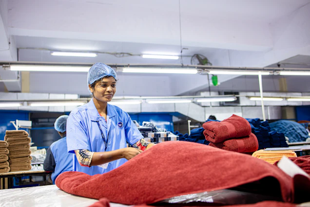 Woman in factory working with fabric rolls.