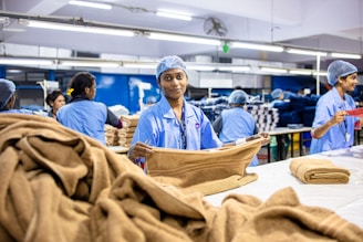 Workers fold towels in a factory setting.