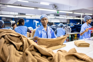 Workers fold towels in a factory setting.