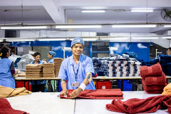 Workers fold towels in a factory setting.
