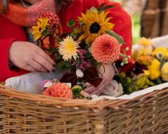 Woman arranges vibrant flowers in a wicker basket.
