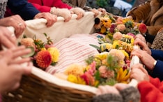 People carry a flower-covered wicker casket.