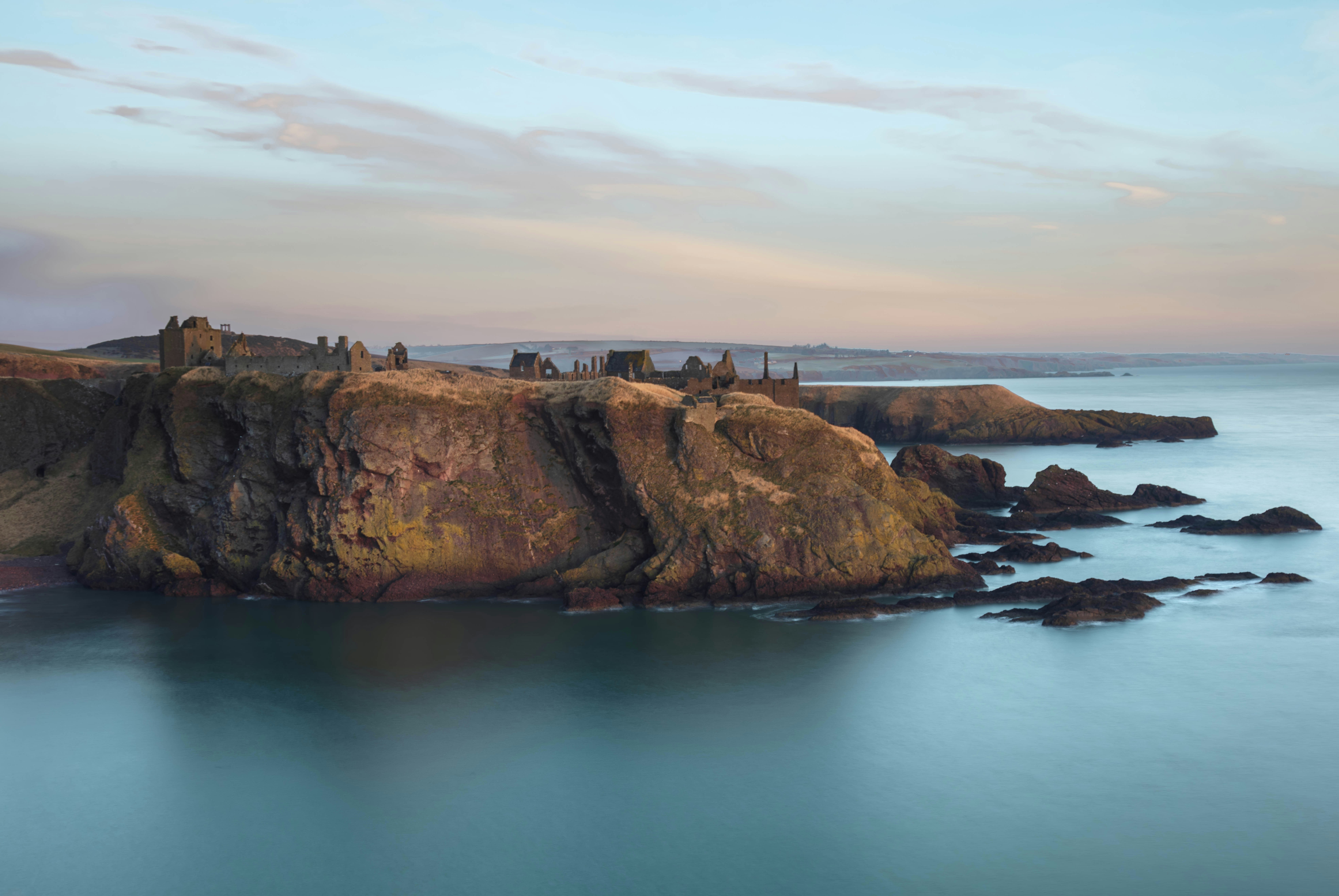 Coastal cliffs meet the tranquil ocean waters at sunset.