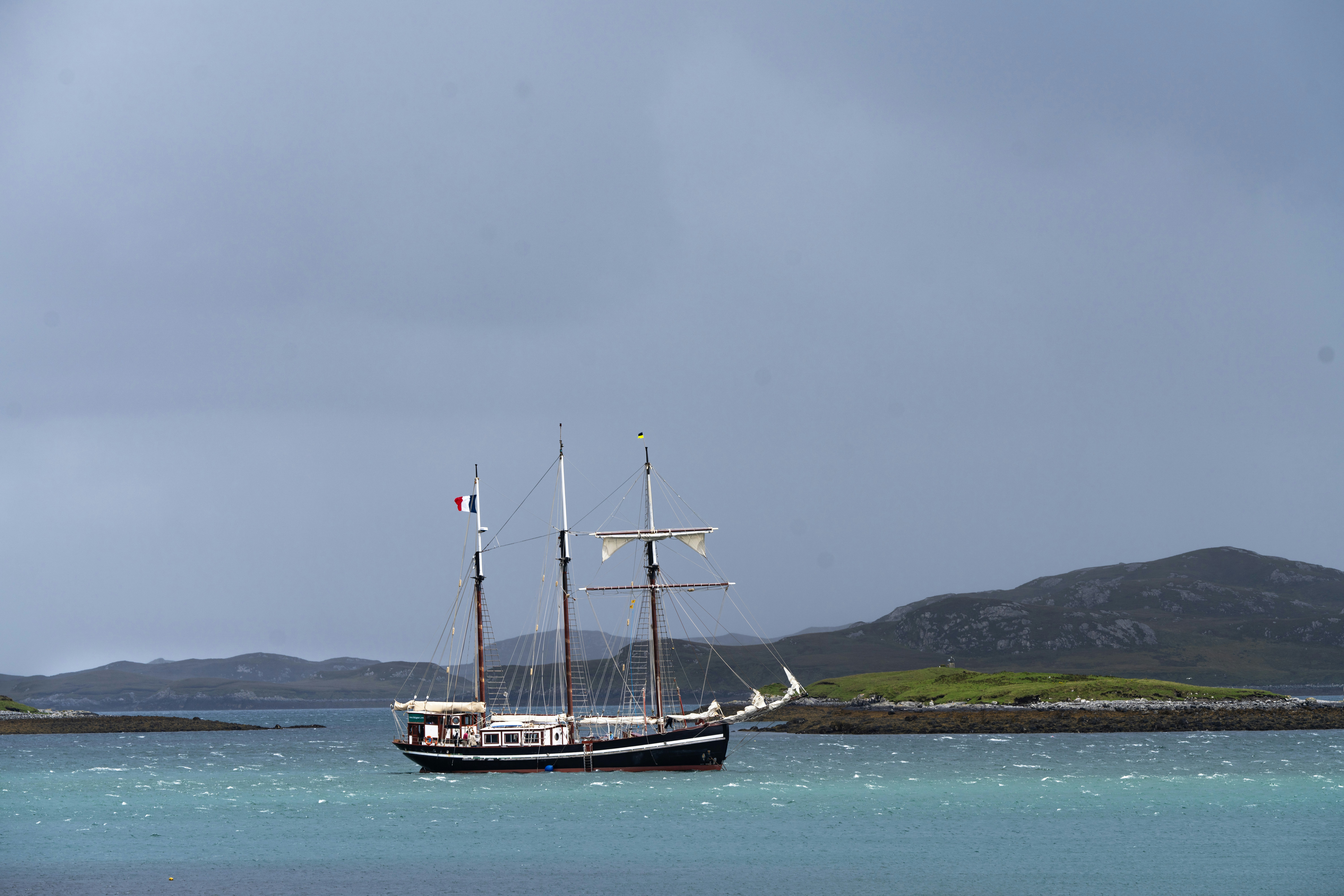 A sailboat floats on turquoise water near the islands.